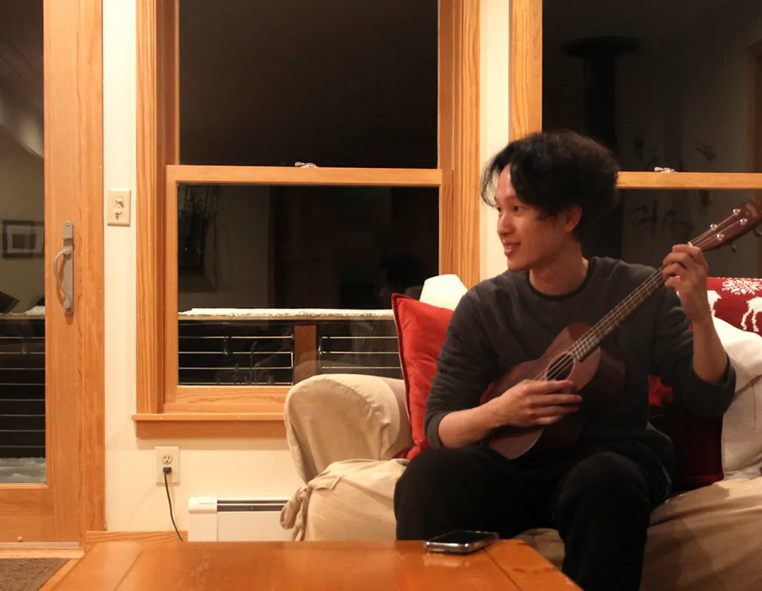 Playing ukulele in a lake-side cabin